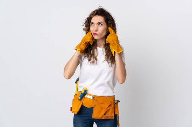 Beyaz arka planda izole edilmiş genç elektrikçi hayal kırıklığına uğramış ve kulaklarını kapatmış.