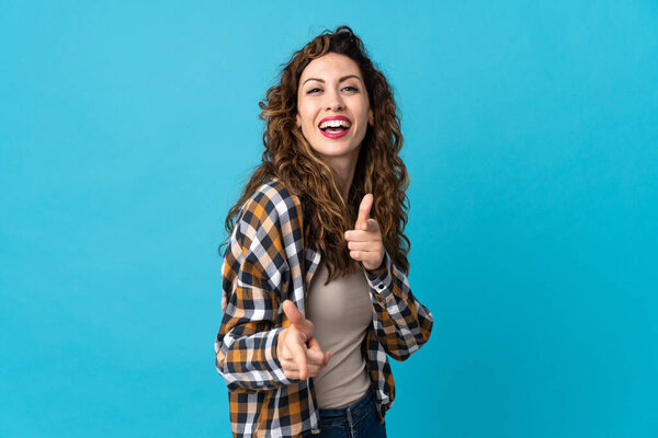 Young caucasian woman isolated on blue background pointing to the front and smiling