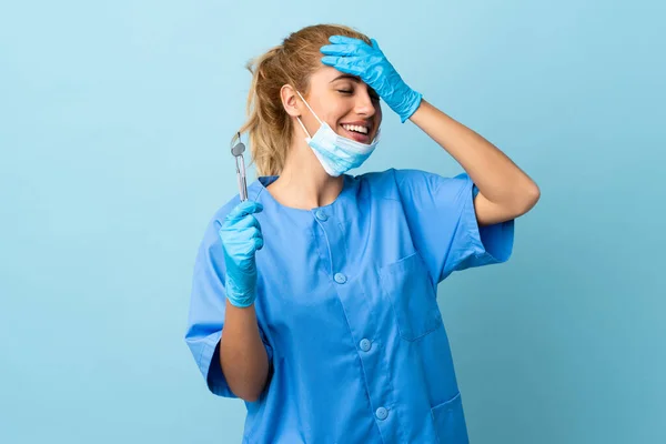 Junge Zahnärztin Hält Werkzeug Vor Isoliertem Blauen Hintergrund Und Lacht — Stockfoto