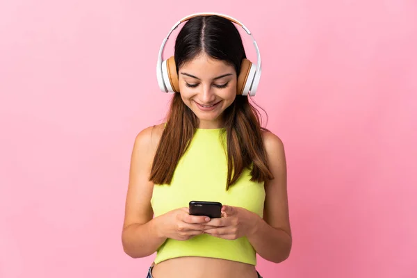 Joven Mujer Caucásica Aislada Sobre Fondo Rosa Escuchando Música Mirando —  Fotos de Stock