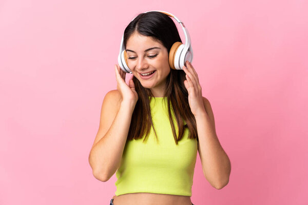 Young caucasian woman isolated on pink background listening music and singing
