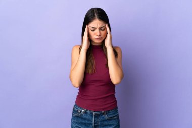 Mor arka planda başağrısı olan genç beyaz bir kadın.