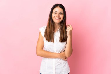Pembe arka planda izole edilmiş genç beyaz kadın gülüyor.