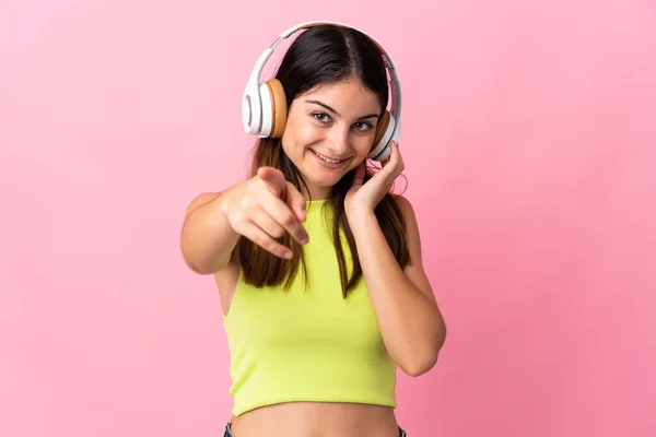 Joven Mujer Caucásica Aislada Sobre Fondo Rosa Escuchando Música Señalando —  Fotos de Stock