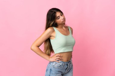 Pembe arka planda izole edilmiş beyaz bir kadın gayret gösterdiği için sırt ağrısı çekiyor.