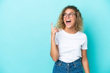 Mavi arka planda izole edilmiş kıvırcık saçlı kız parmağını kaldırarak çözümü bulmaya çalışıyor.