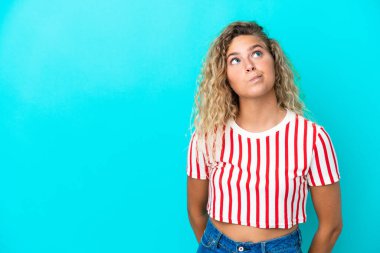 Kıvırcık saçlı kız mavi arka planda izole edilmiş ve yukarı bakıyor.
