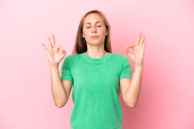 Zen pozisyonunda pembe arka planda izole edilmiş genç bir İngiliz kadın.