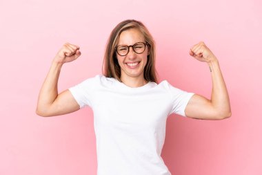 Pembe arka planda izole edilmiş genç İngiliz kadın güçlü bir jest yapıyor.