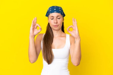 Zen pozunda sarı arka planda izole edilmiş genç İngiliz kadın.