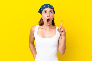 Sarı arka planda izole edilmiş genç bir İngiliz kadın, bir fikrin suçluyu işaret ettiğini düşünüyor.