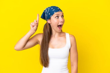 Sarı arka planda izole edilmiş genç İngiliz kadın parmağını kaldırarak çözümü anlamaya çalışıyor.