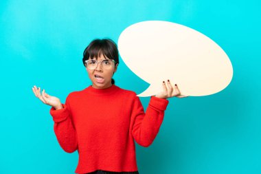 Mavi arka planda izole edilmiş genç bir kadın elinde şaşırmış bir ifadeyle boş bir konuşma balonu tutuyor.