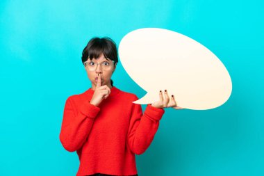 Mavi arka planda izole edilmiş genç bir kadın elinde boş bir konuşma balonuyla sessizce hareket ediyor.