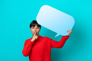 Mavi arka planda izole edilmiş genç bir kadın elinde boş bir konuşma balonuyla sessizce hareket ediyor.