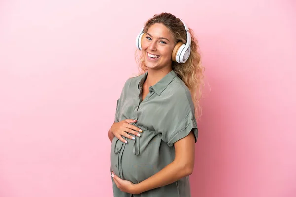 Chica Con Pelo Rizado Aislado Sobre Fondo Rosa Embarazada Escuchar —  Fotos de Stock