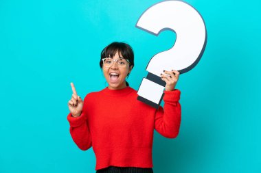 Mavi arka planda izole edilmiş genç bir kadın soru işareti simgesi taşıyor