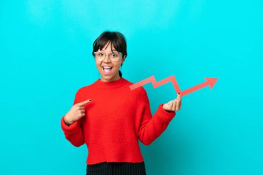 Mavi arka planda izole edilmiş genç bir kadın, elinde şaşırmış bir ifadeyle yükselen bir oku tutuyor.