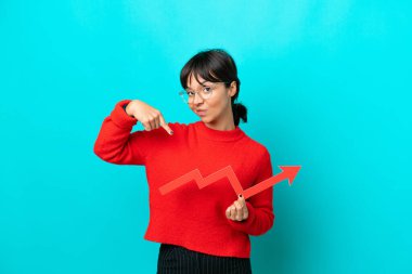 Mavi arka planda izole edilmiş genç bir kadın elinde yükselen bir oku tutuyor ve ona doğrultuyor.