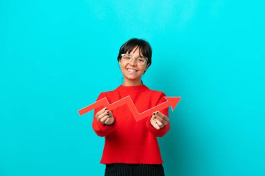 Mavi arka planda izole edilmiş genç bir kadın elinde mutlu bir ifadeyle yükselen bir ok tutuyor.