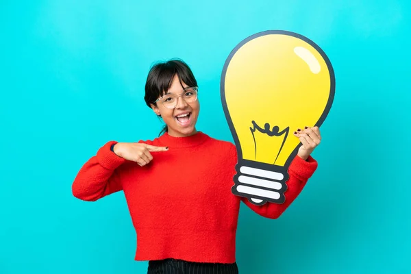 Young Woman Isolated Blue Background Holding Bulb Icon Pointing — Stock Photo, Image