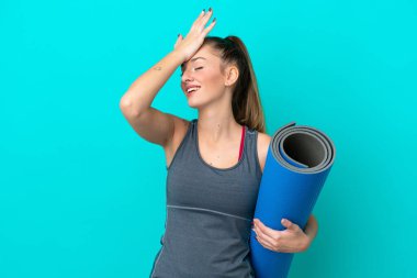 Mavi arka planda izole edilmiş bir minderi tutarak yoga derslerine giden beyaz bir kadın bir şeyin farkına vardı ve çözümü amaçladı.