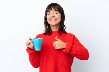 Beyaz arka planda izole edilmiş bir fincan kahve tutan beyaz bir kadın baş parmak işareti yapıyor.