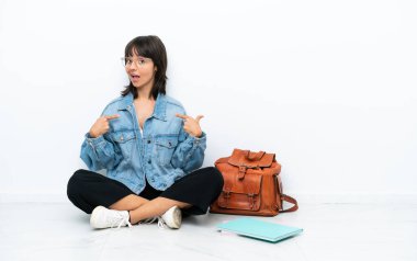 Genç bir kız öğrenci beyaz arka planda tek başına oturuyor gururlu ve kendinden memnun.