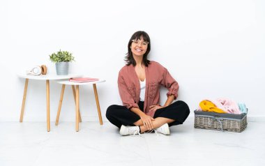 Genç ırk katlayan kadın, beyaz arka planda soyutlanmış, kolları kalçasında ve gülümseyerek oturuyor.