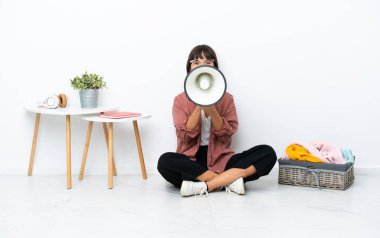 Genç ırk katlayan kadın, beyaz arka planda soyutlanmış bir şekilde yerde oturmuş megafonla bağırıyor.
