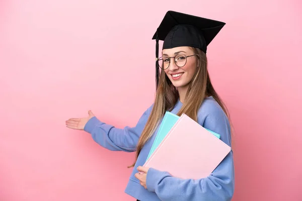 Jovem Estudante Usando Chapéu Pós Graduação Isolado Fundo Rosa Estendendo — Fotografia de Stock
