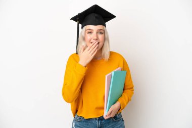 Beyaz arka planda izole edilmiş beyaz bir üniversite mezunu genç bir kadın mutlu ve ağzı kapalı gülümsüyor.