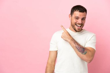 Pembe arka planda izole edilmiş genç Brezilyalı adam şaşırmış ve işaret ediyor.
