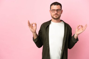 Zen pozisyonunda pembe arka planda izole edilmiş genç Brezilyalı adam.