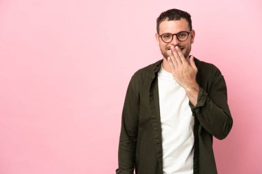 Pembe arka planda izole edilmiş genç Brezilyalı adam mutlu ve gülümsüyor.