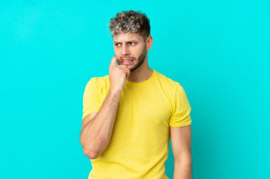 Genç yakışıklı beyaz adam mavi arka planda izole edilmiş gergin ve korkmuş.