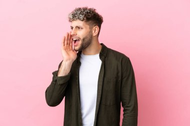 Pembe arka planda izole edilmiş yakışıklı beyaz adam ağzı sonuna kadar açık bağırıyor.