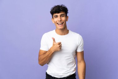 Arjantinli genç adam arka planda izole edilmiş bir şekilde baş parmak hareketi yapıyor.