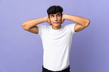 Arjantinli genç adam arka planda izole edilmiş hayal kırıklığına uğramış ve kulaklarını kapatmış.