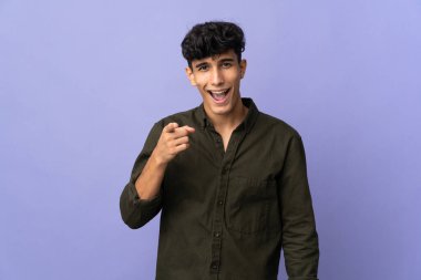 Arjantinli genç adam arka planda izole edilmiş şaşırmış ve ön tarafı işaret ediyor.