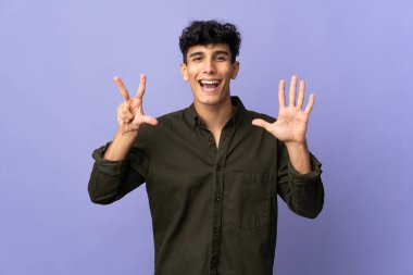 Arjantinli genç adam arka planda izole edilmiş. Parmaklarıyla sekizi sayıyor.