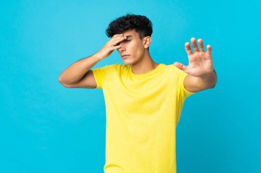 Arjantinli genç bir adam arka planda izole edilmiş jest yapıyor ve yüzünü kapatıyor.