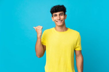 Arka planda izole edilmiş genç Arjantinli bir adam bir ürün sunmak için kenarı işaret ediyor