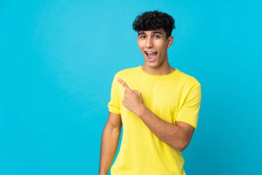 Arka planda izole edilmiş genç Arjantinli adam şaşırmış ve işaret ediyor.