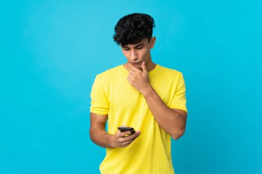 Arjantinli genç adam arka planda izole edilmiş düşünüyor ve bir mesaj gönderiyor.