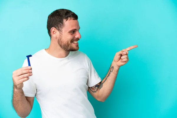 Brazylijczyk Golący Brodę Niebieskim Tle Wskazując Palcem Bok Prezentując Produkt — Zdjęcie stockowe