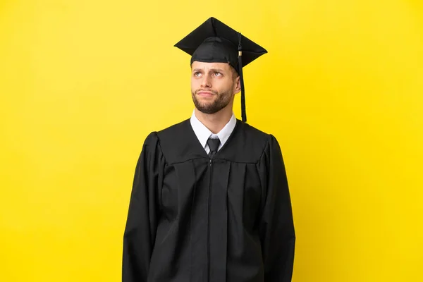 Junger Universitätsabsolvent Kaukasischer Mann Isoliert Auf Gelbem Hintergrund Und Schaut — Stockfoto