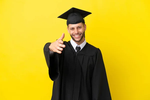 Junger Universitätsabsolvent Kaukasischer Mann Isoliert Auf Gelbem Hintergrund Beim Händeschütteln — Stockfoto