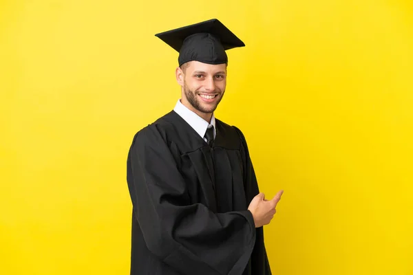 Νεαρός Απόφοιτος Πανεπιστημίου Καυκάσιος Άνδρας Απομονωμένος Κίτρινο Φόντο Που Δείχνει — Φωτογραφία Αρχείου