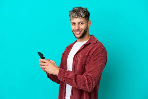 Mavi Arka Planda Izole Edilmiş Yakışıklı Beyaz Adam Cep Telefonuyla — Stok fotoğraf